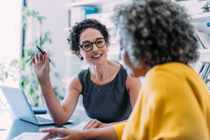 Two businesswomen sharing ideas on contingent workforce strategy during a meeting in the office.