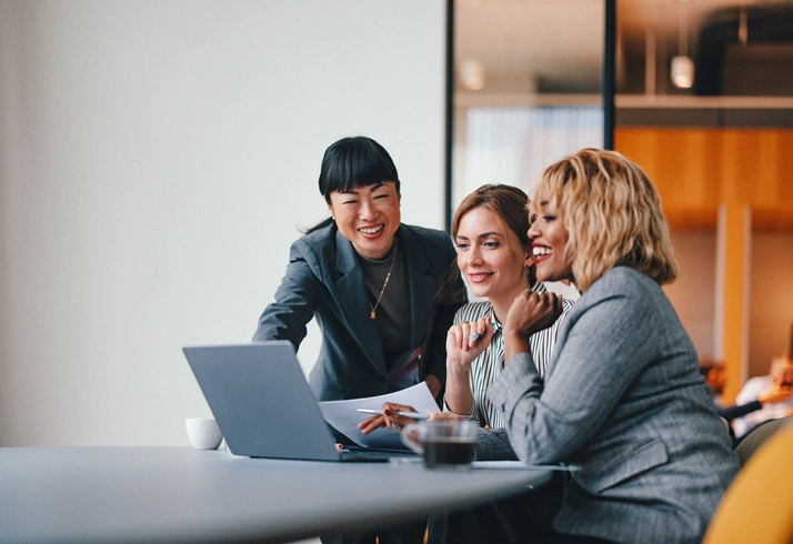 Three professionals in an office discussing 'what is a managed service provider' while reviewing documents and a laptop.